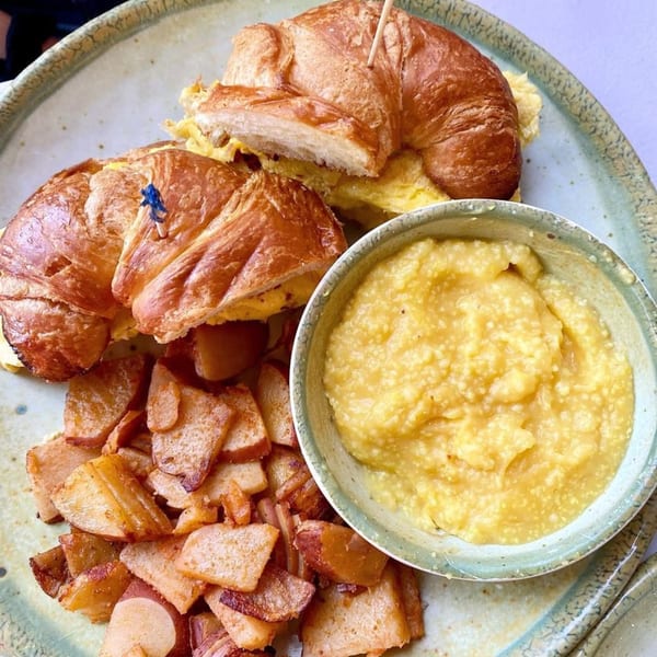 Janik's Cafe breakfast with scrambled egg croissants, home fries, and a side of grits.