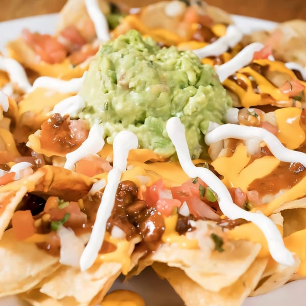 Janik's Cafe nachos with guacamole, cheese sauce, salsa, and sour cream drizzle.