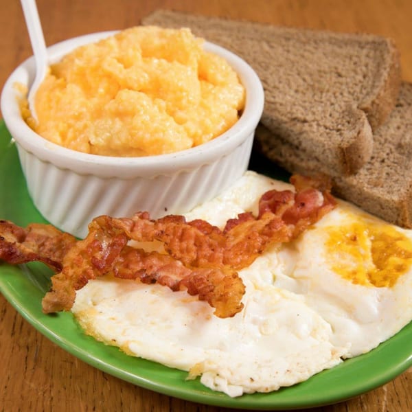 Janik's Cafe breakfast with cheesy grits, crispy bacon, fried eggs, and whole wheat toast.